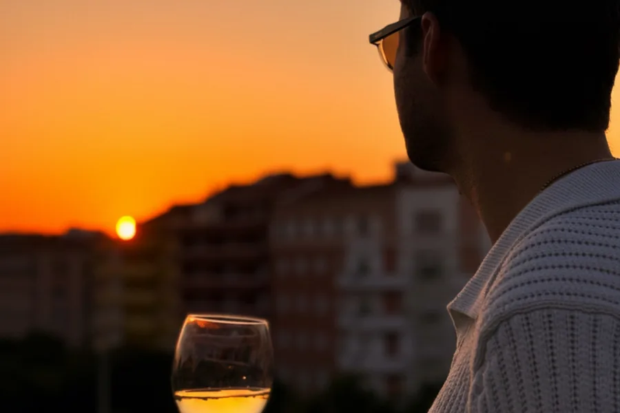 Guest holding a glass of Portuguese wine at sunset overlooking Lisbon.