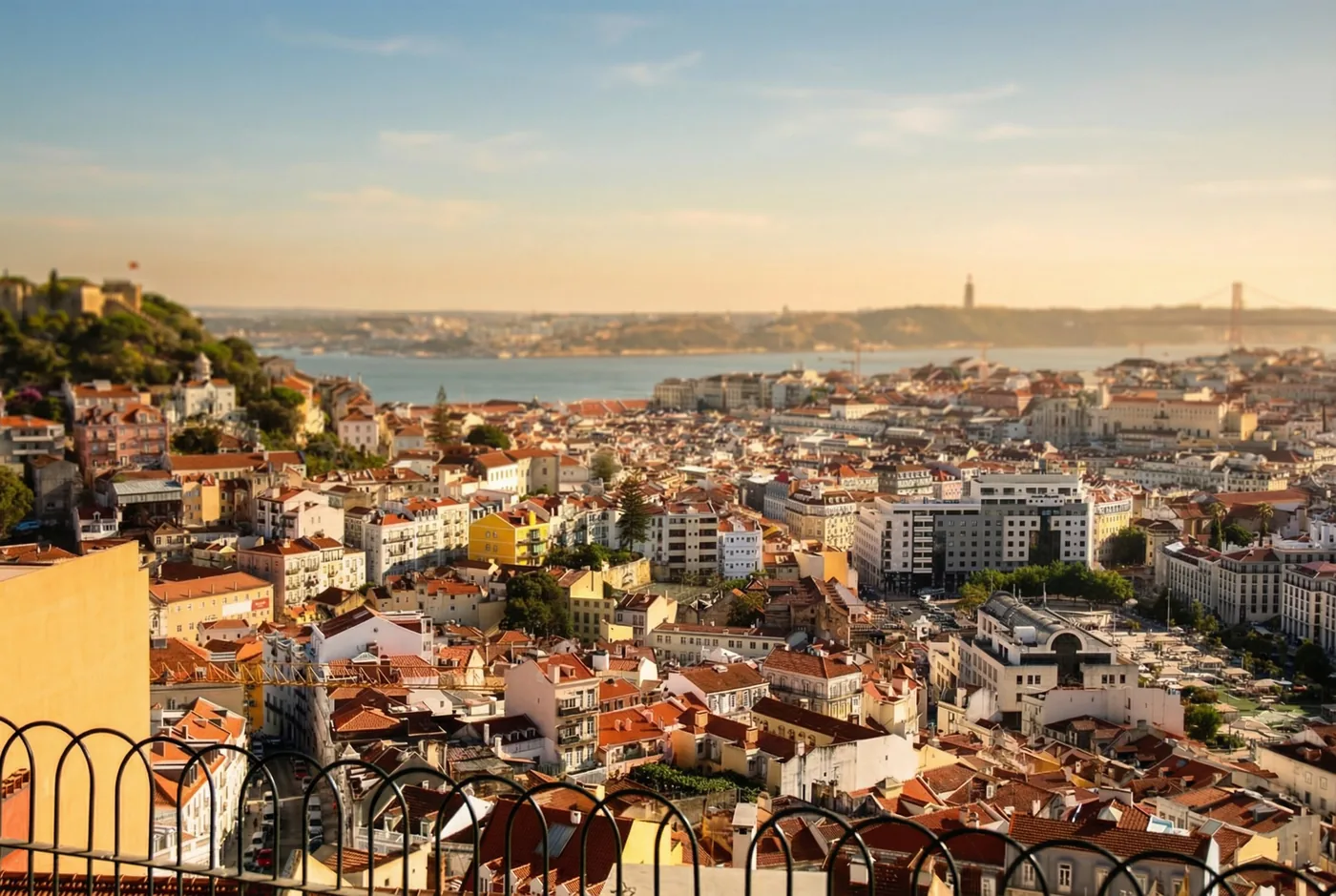 Panoramic view of Lisbon's historic rooftops, the Tagus River and the 25 de Abril Bridge.