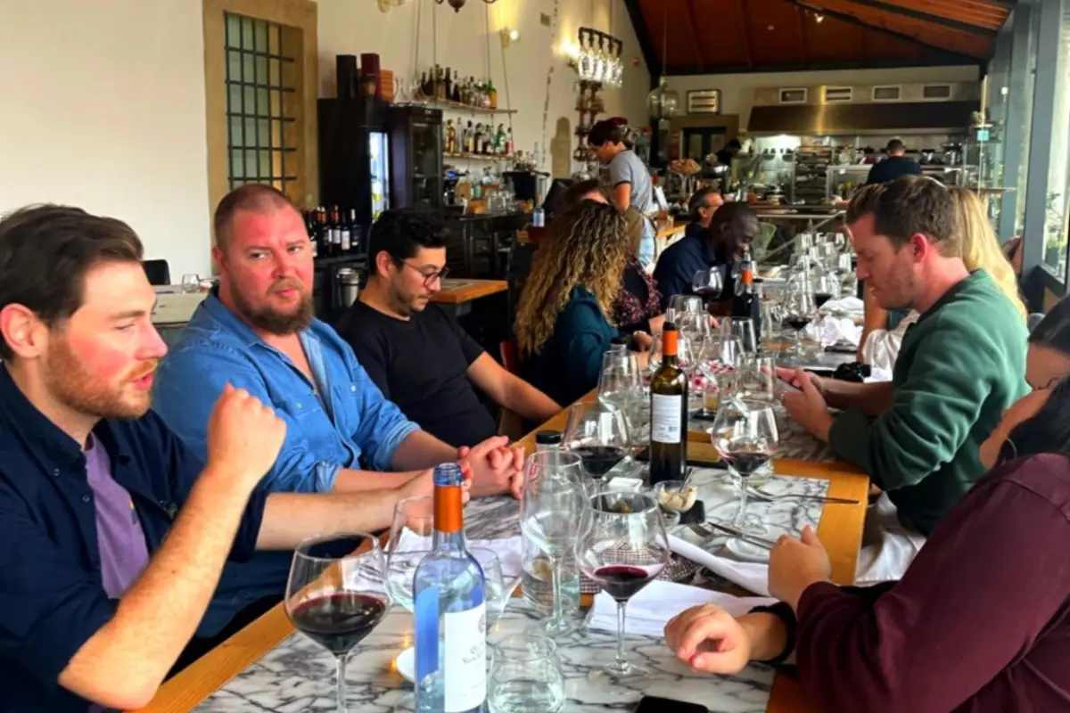 Guests enjoying a private lunch with Portuguese winemakers, sharing local wines and regional cuisine in a winery setting.